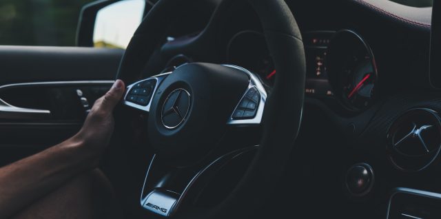 person holding on black steering wheel inside car